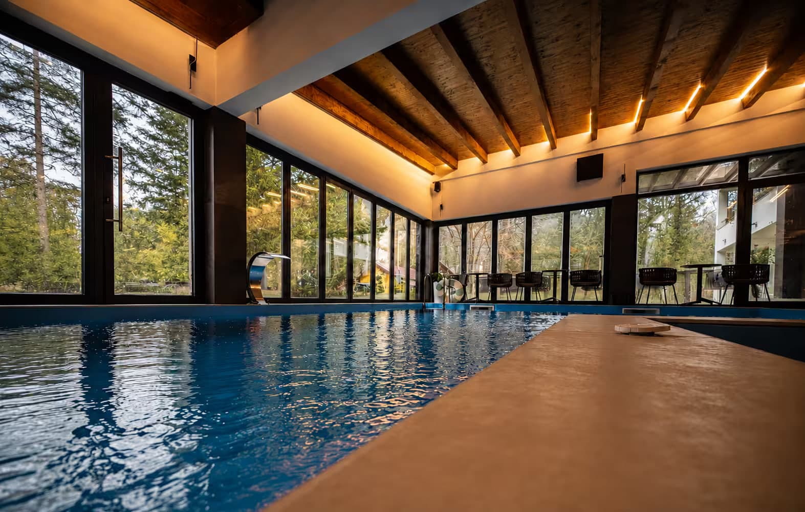 Zatvoreni bazen Wellness & Spa centra sa drvenim plafonom i staklenim zidovima prema šumi